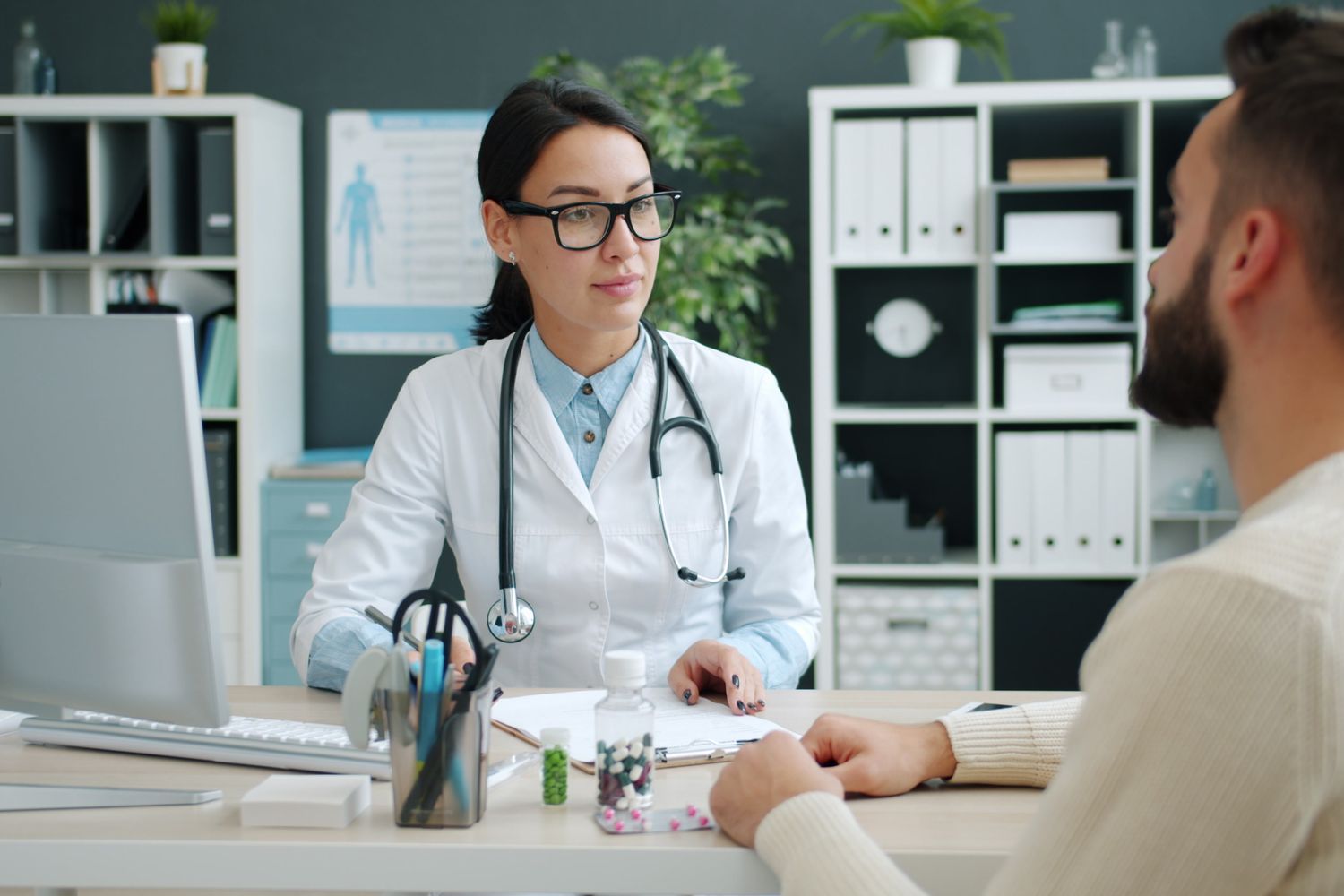 An Asian clinician speaking with a visitor in a consultation room